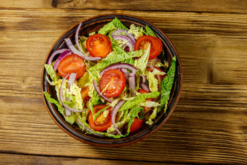 Healthy salad with savoy cabbage, cherry tomato, red onion and olive oil on wooden table. Top view