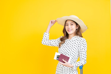 beautiful asia woman happy smiley holding passport bording pass. tourist girl standing with luggage with yellow background.
