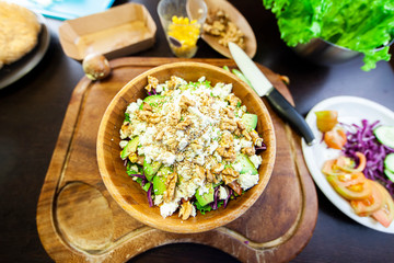 Wooden bowl with mixed salad, cheese and fresh fruit