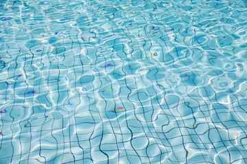 Sun reflection in clear clean and bright blue water of swimming pool, Shining blue water ripple background, Aqua texture, pattern