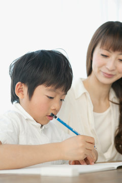 Woman assisting boy writing in notebook