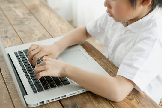 Boy using laptop at wooden table