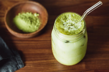 Matcha green tea latte in a glass jar with glass tube. Healthy clean eating concept.