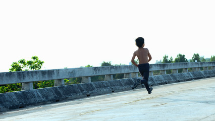 A little boy runs along the bridge on the beach.