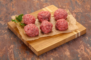 Raw meatball over wooden background