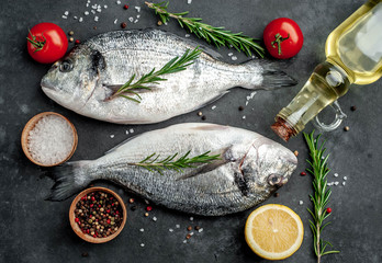Fresh dorado fish with spices and ingredients tomato, razmorin, sunflower oil, lemon for cooking on a stone background