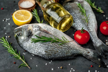 Fresh dorado fish with spices and ingredients tomato, razmorin, sunflower oil, lemon for cooking on a stone background