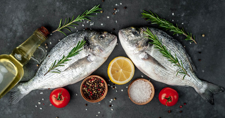 Fresh dorado fish with spices and ingredients tomato, razmorin, sunflower oil, lemon for cooking on a stone background