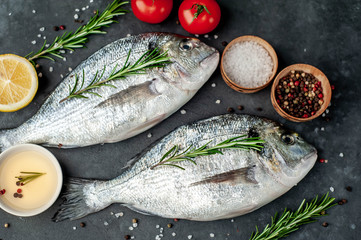 Fresh dorado fish with spices and ingredients tomato, razmorin, sunflower oil, lemon for cooking on a stone background with copy space for your text