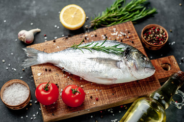Fresh dorado fish with spices and ingredients tomato, razmorin, sunflower oil, lemon for cooking on a stone background