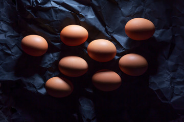 Eight brown eggs on a dark background for coloring.