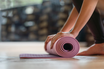 Close-up rolling yoga mat after working out at fitness ,sport and training club.Diversity People Exercise Class Relax Concept - obrazy, fototapety, plakaty