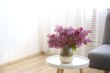 Flower vases sitting inside of window - blooming shrubbery and spring scenery outside of window.