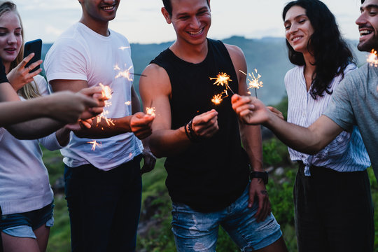 Group of friends enjoying out with sparklers while camping in forest on holidays vacation in summer,Adventure travel concept.