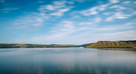 picturesque summer time morning landscape of peaceful lake reservoir water surface horizon background national park hill land and blue sky cloudy fuzzy motion concept effect