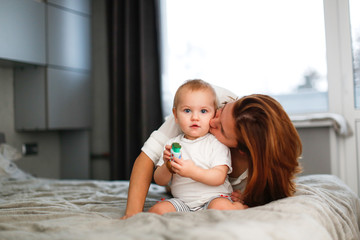 mom on bed plays with Toddler baby, lifestyle