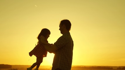 Fototapeta na wymiar father and little daughter whirl in dance at sunset. concept of happy childhood. Dad is dancing with child in her arms. happy child plays with his father at sunset. concept of happy family