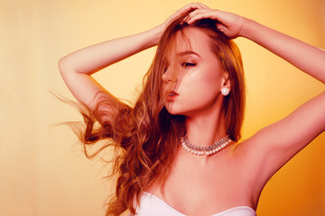 Obraz premium Fashion photo of a beautiful girl with creative make-up with pearls. Girl in orange color with long hair posing beautifully. Dance.