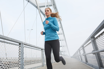 Blond hair female jogging outdoors on cold winter day.