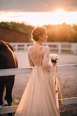 Young bride stands unfolded in profile demonstrating a wedding hairstyle in backlight. Flare effect.