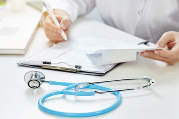 Closeup of a female doctor writing a prescription