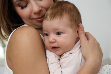 Young woman with her little baby resting after breast feeding at home, closeup