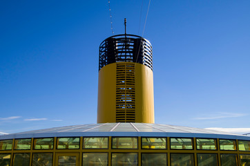 Yellow funnel and outdoor deck of Italian cruise ship or cruiseship liner with blue sky with...