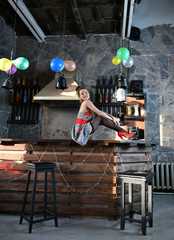 Naklejka na ściany i meble beautiful pin-up girl in a gray-red dress sitting on a bar table