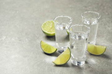 Mexican Tequila shots with salt and lime slices on grey table