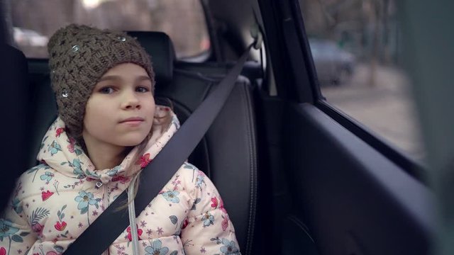 Little girl in a cap looking out the car window.
