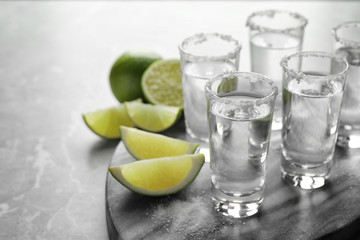 Fototapeta na wymiar Mexican Tequila shots, lime slices and salt on grey marble table