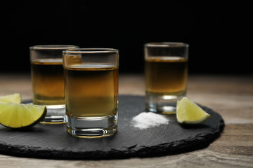 Mexican Tequila shots, lime slices and salt on wooden table