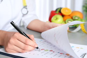 Female nutritionist with list of products at table, closeup
