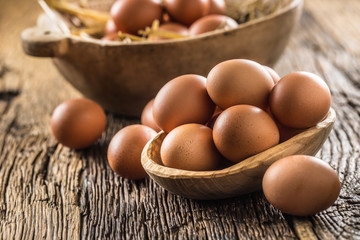 Fresh raw eggs in wooden bowl on rustic wooden table