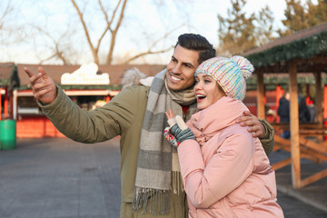 Happy couple in warm clothes at winter fair. Christmas season