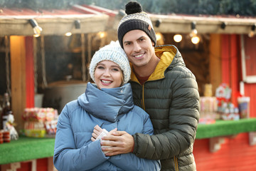 Happy couple in warm clothes at winter fair. Christmas season