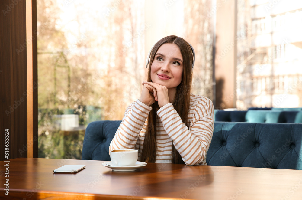 Canvas Prints Woman listening to audiobook at table in cafe