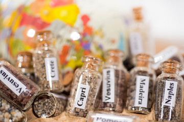 Glass test-tube with sand of different summer vacation countries. Located in sand with small globe.