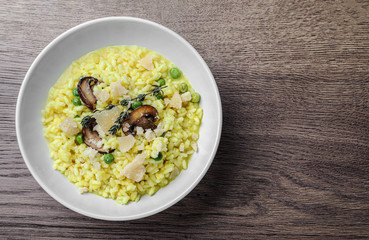 Delicious risotto with cheese and mushrooms on wooden table, top view. Space for text