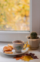 cup of coffee and cactus in a pot on the windowsill