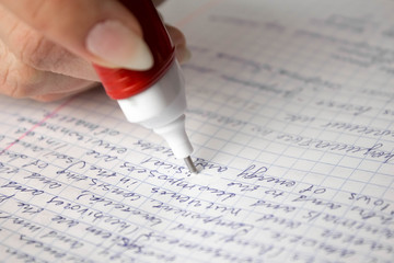 White stationery corrector correct the text in the notebook. Close up. Isolated on a white...