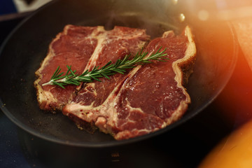 Raw Fresh Marbled Meat Beef on a grill pan ready for cooking. Man cooking beef steaks. Male hands holding a grill pan with beef steaks on kitchen