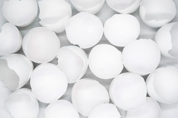 Close up top view of lots of broken white eggshells on a white background// Top view of many broken white eggshells on a white background
