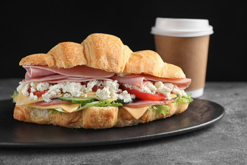 Tasty croissant sandwich with ham on grey table