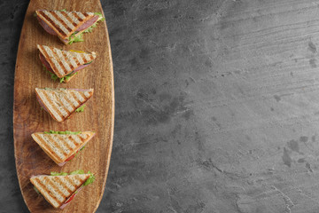 Tasty sandwiches with ham on grey table, top view. Space for text