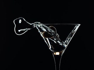Silhouette of martini with green olives on a black background.