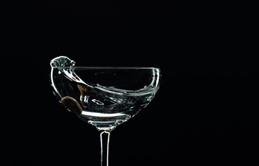 Silhouette of martini with green olive on a black background.