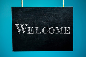 Chalk board is hanging with the inscription "Welcome" on a blue background. copy space