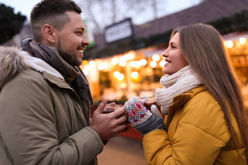 Happy couple with mulled wine at winter fair