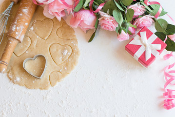 Cooking homemade cookies shaped hearts withgift and pink roses on a white background